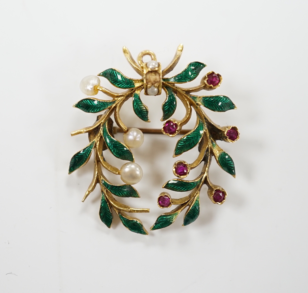 A yellow metal, green enamel, ruby and seed pearl cluster set wreath pendant brooch, 29mm, gross weight 6.9 grams.